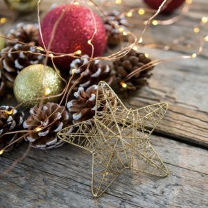 Close-up of star, rice lights, bauble ball and pine cone on wooden plank during christmas time